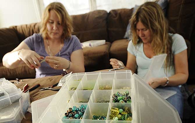 Longtime friends Angie Neiman, left, and Kristen Prather work side by side while creating various pieces of handmade jewelry in Prather's home.