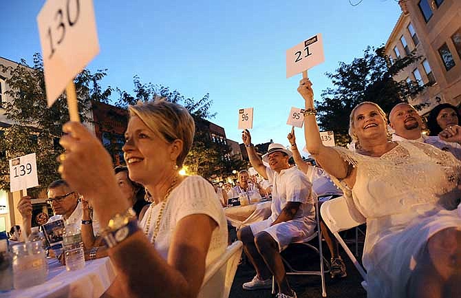 Event attendees raise their paddles as bidding begins for one of several items during the Piccadilly auction portion of the Downtown Jefferson City Piccadilly in White fundraiser on Aug. 2, 2014.