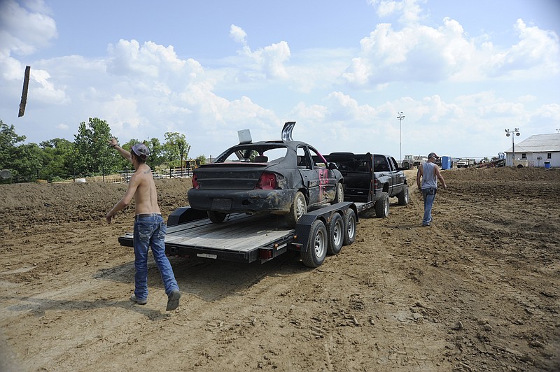 From left, Cody Scurlock and Cody Ryder, both of Eldon, pick up Ryder's car and clean up some of the debris on Sunday that was left from Saturday night's Figure 8 competition at the Jefferson City Jaycees Cole County Fair. "I didn't win, but I had fun," Ryder said. He plans to compete at a similar event in California this weekend.