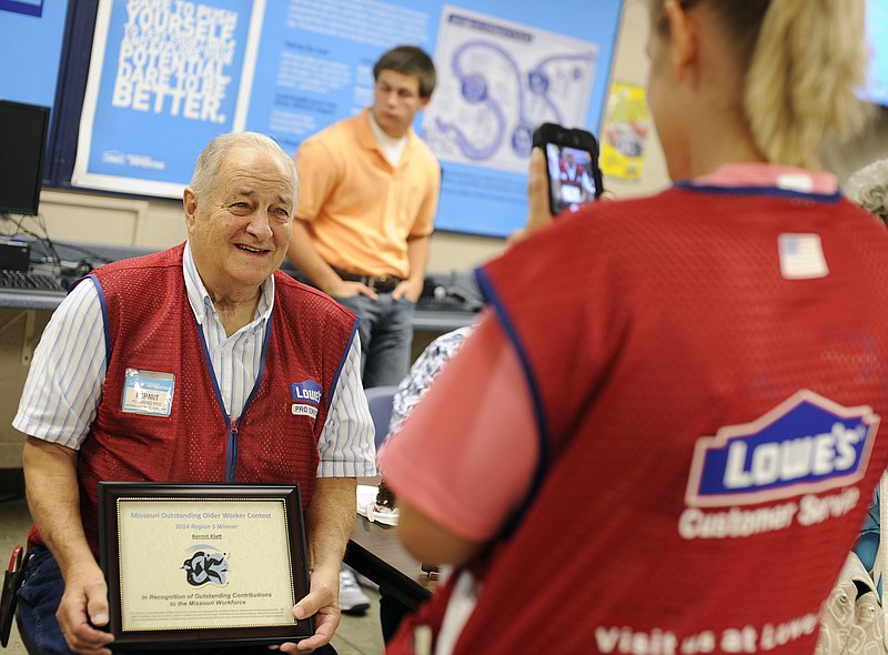 Longtime Lowe's employee Kermit Klatt smiles as his coworker, delivery manager Jenny Luebbert snaps a photo during an awards ceremony on Tuesday held in his honor after he was named the Region 5 winner in the 2014 Missouri Outstanding Older Worker Contest.