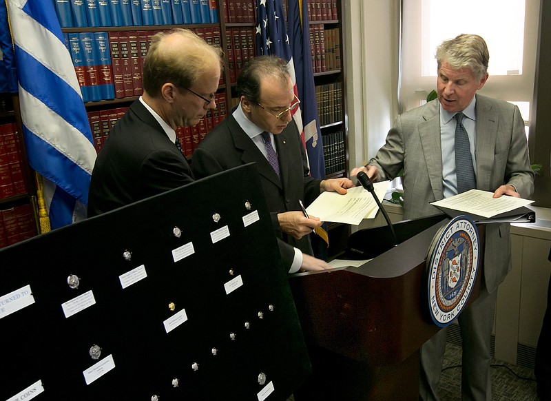 Greek Ambassador to the U.S. Christos Panagopoulos, center, and Manhattan District Attorney Cyrus Vance Jr., right, accompanied by ICE Homeland Security Investigations Deputy Agent in Charge Glenn Sorge, sign documents during a repatriation ceremony of ancient Greek coins, in New York, on Monday.