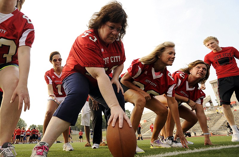 LeAnn McCarthy gets set to snap the ball to quarterback Staci Darr as Jay moms practice running a play on offense from the victory formation Wednesday during the annual Mom's Night at Adkins Stadium.