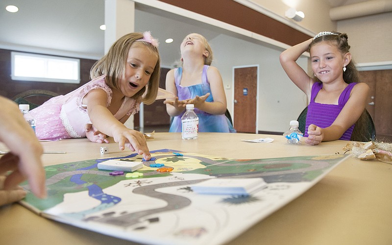 Elise Klein, 6, and Cheyenne Studer, 7, both of Fulton, react as Shelby Studer, 5, moves five spaces forward in a fairy-themed board game Thursday at the John C. Harris Community Center. The girls attended a fairy festival hosted by the new non-profit organization, Creative Kids Outreach, which premiered in July. 