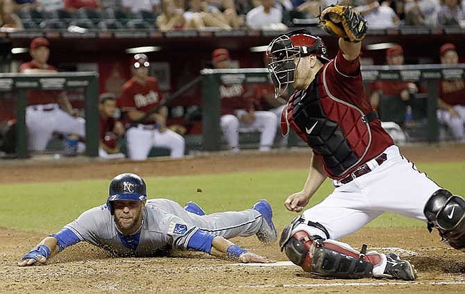 Kansas City Royals' Alex Gordon, left, touches home plate to score a run as Arizona Diamondbacks' Miguel Montero, right, catches a late throw during the third inning of a baseball game on Wednesday, Aug. 6, 2014, in Phoenix. 