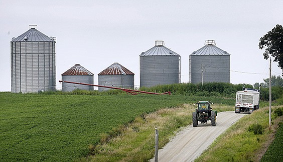 A farmer drives his tractor past a soybean field Aug. 5 toward grain storage bins near Ladora, Iowa. The nation's corn and soybean farmers are on track to produce record crops this year as a mild summer has provided optimum growing conditions.