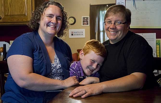 Amanda Bergeron-Bauer, left, and Crystal Bergeron-Bauer pose for a photo in Lincoln, Neb., Friday, Aug. 8, 2014, as their 5 year-old son Emmett joins the picture. Amanda Bergeron-Bauer, 34, and her partner of 15 years, Crystal, have been married less than a year, but went through the process of legally changing their names in 2009, after deciding to have a child. Amanda fears that should anything happen to her, the 5-year-old son she bore could be taken from Crystal, who is not recognized by the state of Nebraska as the boy's legal parent, even though she and Amanda have raised the boy together since his birth. 