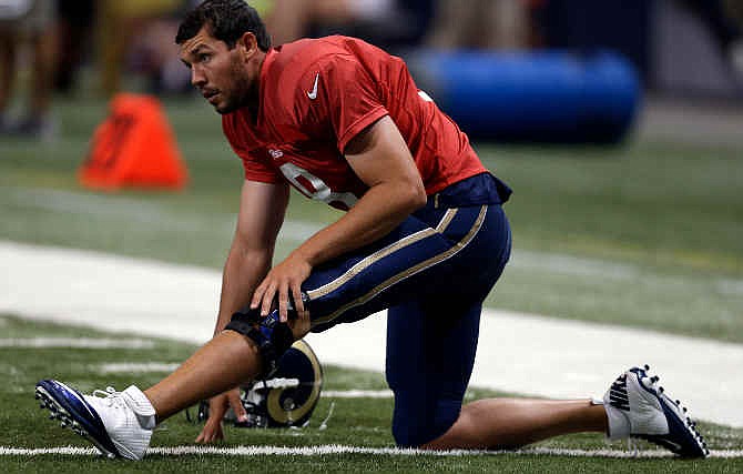 St. Louis Rams quarterback Sam Bradford wears a knee brace as he stretches at the start of practice during NFL football training camp at Edward Jones Dome Saturday, Aug. 2, 2014, in St. Louis. Bradford had surgery on his left knee following an injury that ended his season last year. 