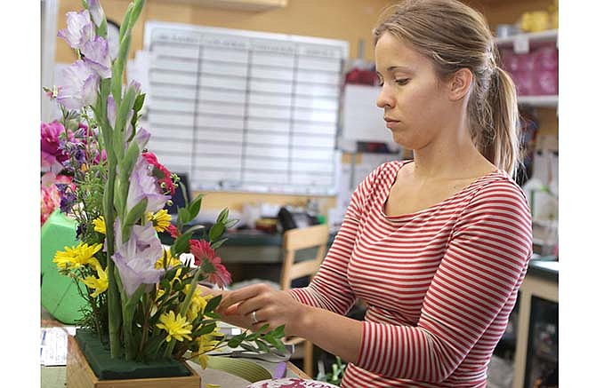 Taylor Cleveland works on a flower arrangement July 17 at Busch's Florist. Cleveland, who has worked there for about 2 and a half years, has an art background.