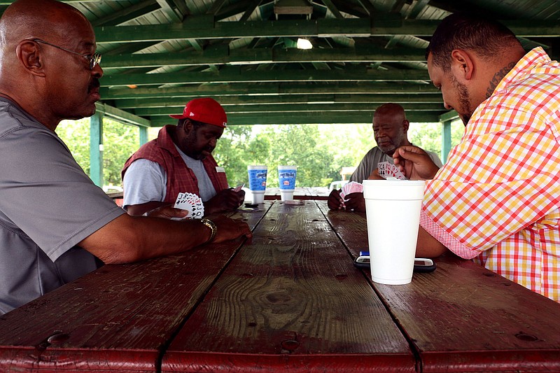 Four men play cards at Carver Park. Several residents in the surrounding community meet at the park just after noon each day to play cards and catch up.