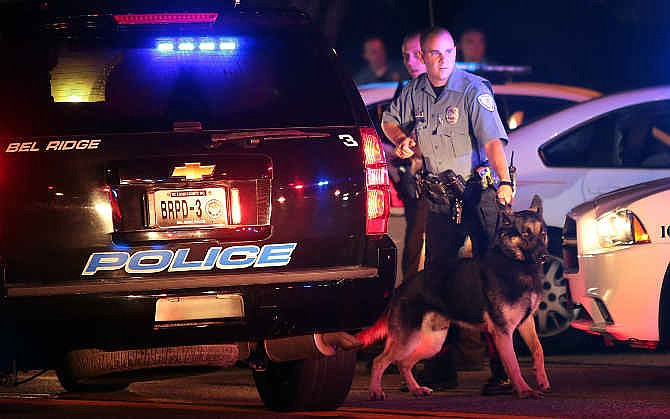 Police officers patrol the area Sunday, Aug. 10, 2014, in Ferguson, Mo. A few thousand people crammed a suburban St. Louis street Sunday night at a vigil for unarmed 18-year-old Michael Brown shot and killed by a police officer, while afterward several car windows were smashed and stores were looted as people carried away armloads of goods as witnessed by an an Associated Press reporter. (AP Photo/St. Louis Post-Dispatch, Robert Cohen)