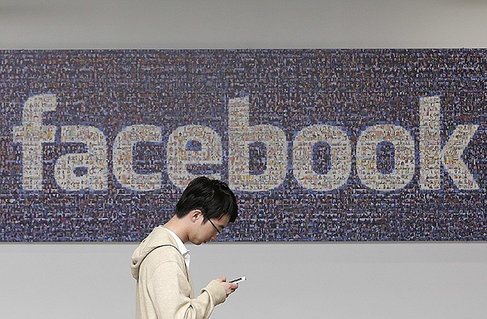 A man walks past a Facebook sign in an office on the Facebook campus in Menlo Park, Calif. 