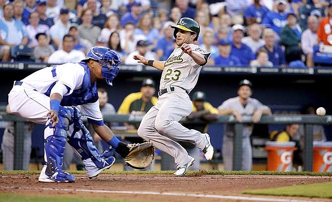 Oakland Athletics' Sam Fuld (23) beats the tag at home by Kansas City Royals catcher Salvador Perez to score on a single by Josh Donaldson during the third inning of a baseball game Tuesday, Aug. 12, 2014, in Kansas City, Mo.