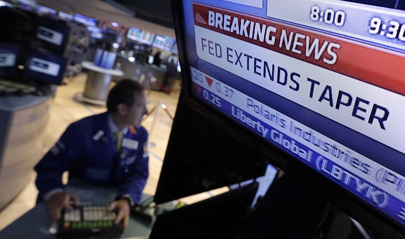 In this June 18, 2014 file photo, a television monitor at a trading post on the floor of the New York Stock Exchange shows the decision of the Federal Reserve. Like with other higher-risk investments, investors have pulled back from junk, or high yield, bonds because they worry about the end of the Federal Reserve's policy near-zero interest rates. Investors expect the central bank to raise rates sometime next year, and that means the value of bonds currently held in portfolios will fall.