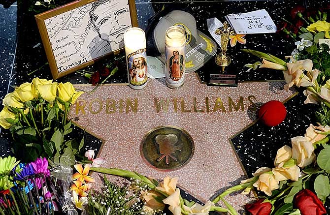 Flowers are placed in memory of actor/comedian Robin Williams on his Walk of Fame star in the Hollywood district of Los Angeles, Monday, Aug. 11, 2014. Williams, a brilliant shapeshifter who could channel his frenetic energy into delightful comic characters like "Mrs. Doubtfire" or harness it into richly nuanced work like his Oscar-winning turn in "Good Will Hunting," died Monday in an apparent suicide. He was 63. Williams was pronounced dead at his San Francisco Bay Area home Monday, according to the sheriff's office in Marin County, north of San Francisco.
