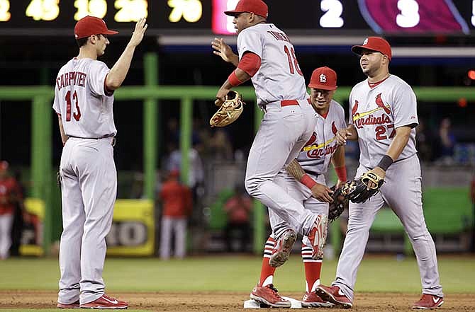 St. Louis Cardinals third baseman Matt Carpenter (13), right fielder Oscar Taveras (18), second baseman Kolten Wong, second from right, and shortstop Jhonny Peralta (27) celebrate after the defeating the Miami Marlins 5-2 during a baseball game, Wednesday, Aug.13, 2014, in Miami.