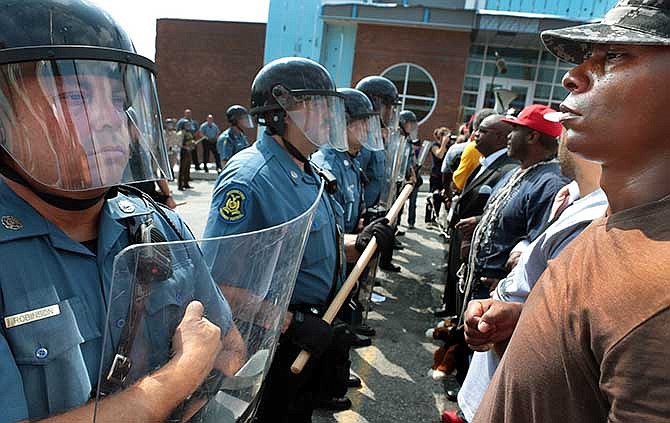 Protestor Boss Bastain of St. Louis locks arms with others as they confront Missouri State Highway Patrol troopers in front of the Ferguson police station on Monday, Aug. 11, 2014.