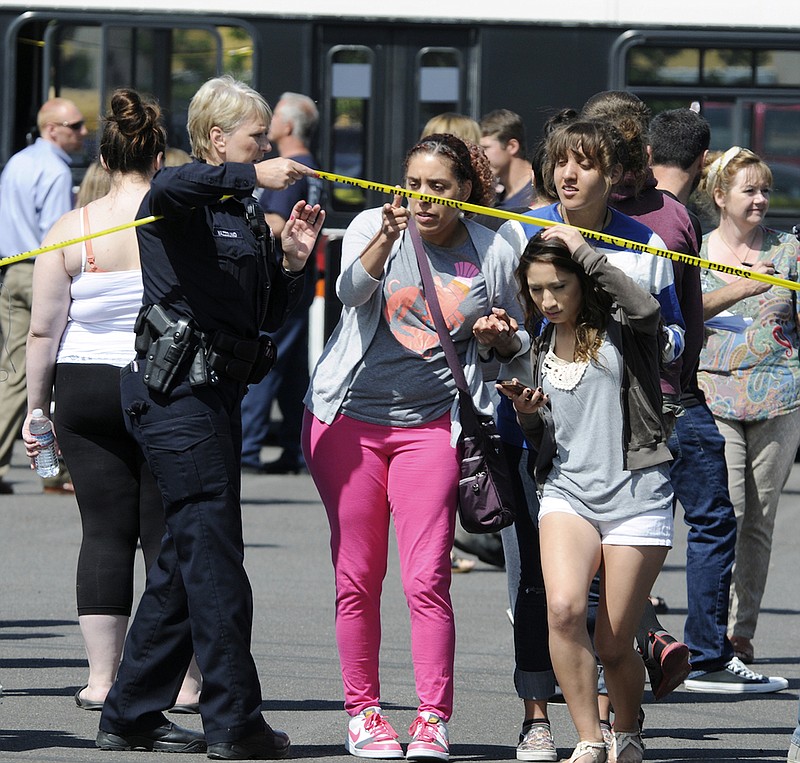 A police officer lifts up police tape as students arrive by bus to meet their parents and/or family at the Fred Meyer grocery store parking lot in Wood Village, Oregon, after a shooting at Reynolds High School, in nearby Troutdale. Police in Washington state are asking the public to stop tweeting during shootings and manhunts to avoid accidentally telling the bad guys what officers are doing.