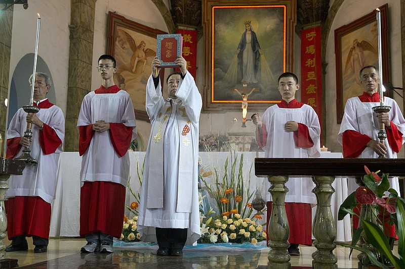 A Chinese priest holds up a bible during a mass Friday at the 400-year-old Cathedral of the Immaculate Conception in Beijing, China. Chinese Catholics cheered Pope Francis' visit to neighboring South Korea, saying they hoped his trip to their region would help end the estrangement between Beijing and the Vatican.