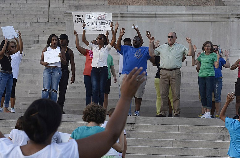 Demonstrators in Jefferson City stand on the south steps of the Missouri Capitol after a march from Lincoln University in response to a police officer's fatal shooting of Michael Brown in Ferguson, Mo.