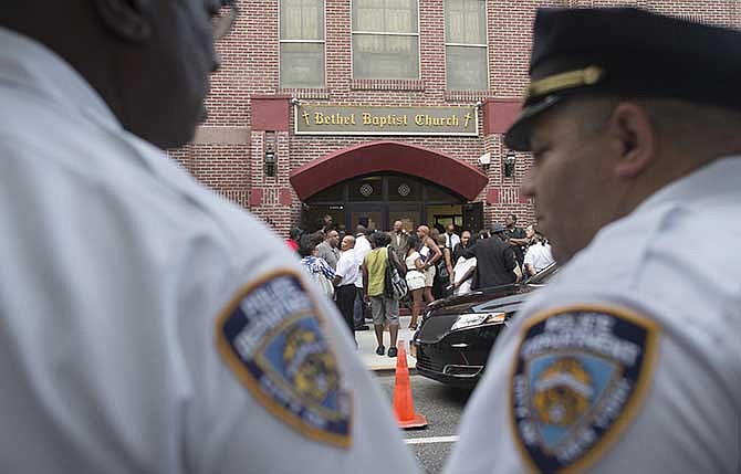 In this July 23, 2014 photo, mourners arrive as ranking NYPD officers stand guard at the funeral service for Eric Garner at Bethel Baptist Church, Wednesday, July 23, 2014, in the Brooklyn borough of New York. There were no violent riots after Garner died as a result of an illegal police chokehold employed on him as he was being arrested. The City's measured response to Garner's death and its engagement with community leaders could be credited with keeping protests and vigils in its aftermath peaceful. 