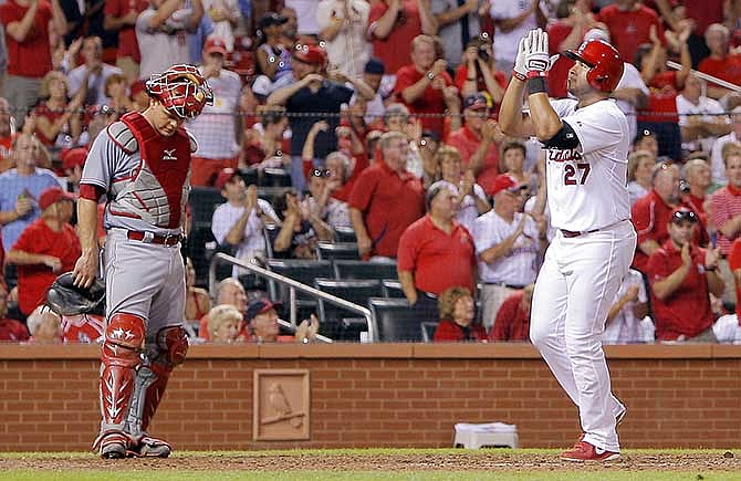 Cincinnati Reds catcher Devin Mesoraco stands near as St. Louis Cardinals' Jhonny Peralta claps his hands while crossing home plate after hitting a solo home run during the sixth inning of a baseball game Tuesday, Aug. 19, 2014, in St. Louis. 