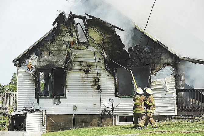 A residential structure fire Wednesday in the 10000 block of E. Railroad Road in Centertown destroyed the home and its contents. Here, firefighters use a pike pole to pull the wiring off the house, which caused the upper floor exterior wall to separate from the structure. 