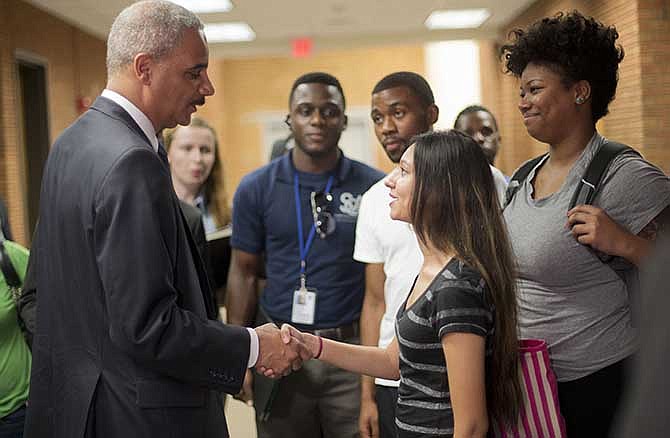 Attorney General Eric Holder shakes hands with Bri Ehsan, 25, right, following his meeting with students at St. Louis Community College Florissant Valley in Ferguson, Mo., Wednesday, Aug. 20, 2014. Holder arrived in Missouri on Wednesday, a small group of protesters gathered outside the building where a grand jury could begin hearing evidence to determine whether a Ferguson police officer who shot 18-year-old Michael Brown should be charged in his death. 