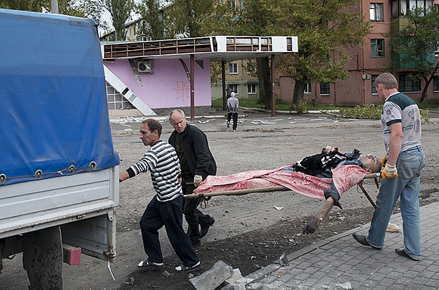 People carry a stretcher with a dead man after shelling by the Ukrainian forces in Makiivka, 16 miles from Donetsk, eastern Ukraine, on Tuesday.  Government troops on Tuesday pressed attacks in the two largest cities held by pro-Russian rebels in eastern Ukraine, as Kiev also pursued diplomatic efforts to resolve the conflict that has killed more than 2,000.