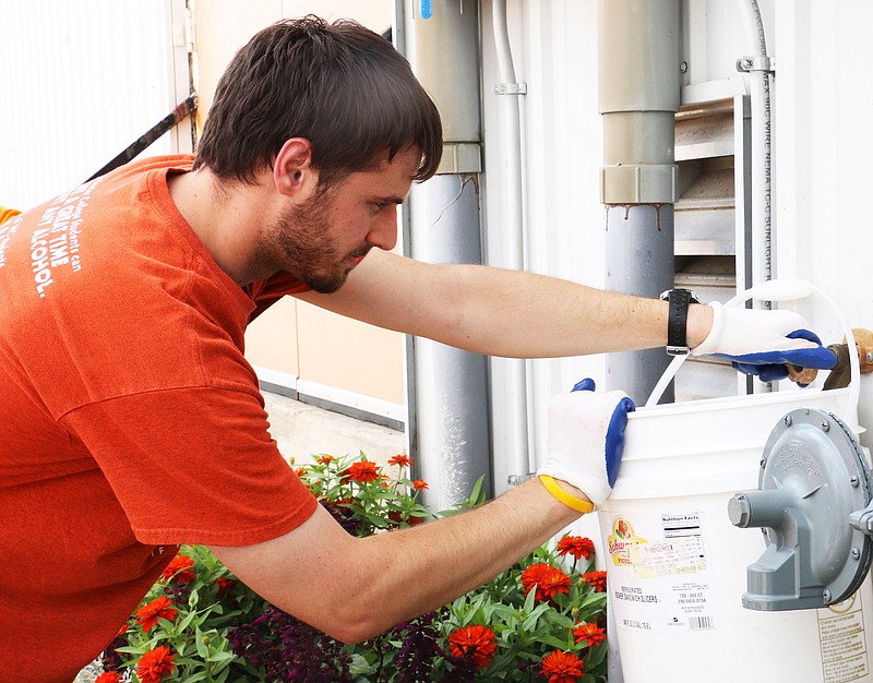 Westminster College senior Spencer Smith fills up a bucket with water to water plants in downtown Fulton on Wednesday, Aug. 20. Smith and about 33 freshman planted and weeded in the Brick District. Westminster sets aside time for freshman to do community service during their orientation week. Smith said he did yard work during orientation week his freshman year, too.