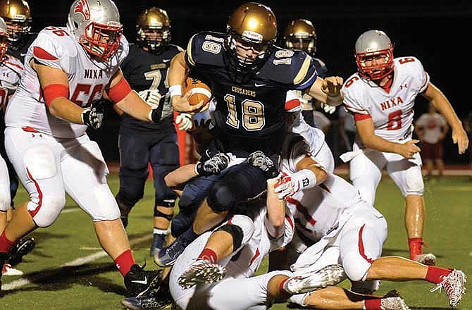 Helias quarterback Alex Faddoul spins over a host of Nixa defenders to pick up extra yardage after scrambling for big gain in the second quarter of Saturday night's matchup at Adkins Stadium in Jefferson City.