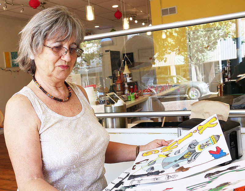 Ana Ravelo looks at the decorations she made in Lulu's Frozen Yogurt and Coffee Shop. The decorations will hang on the walls for the chess classes Sept. 3-5.