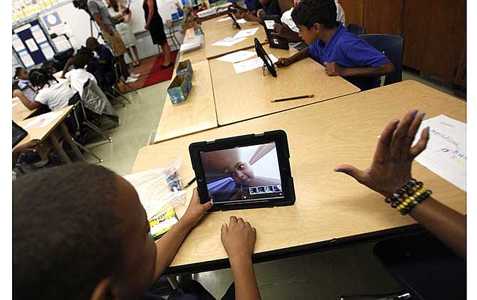 In this August 2013 file photo, Muhammad Nassar Jr. takes a picture of himself using an i-pad during Karen Finkel's class at Broadcrest Elementary School in Carson, Calif. Faced with criticism about the planning and rollout of a $1 billion effort by the Los Angeles Unified School District to provide iPads to all students, Superintendent John Deasy has suspended future use of a contract with Apple Inc. (AP Photo/Los Angeles Times, Bob Chamberlin, File)