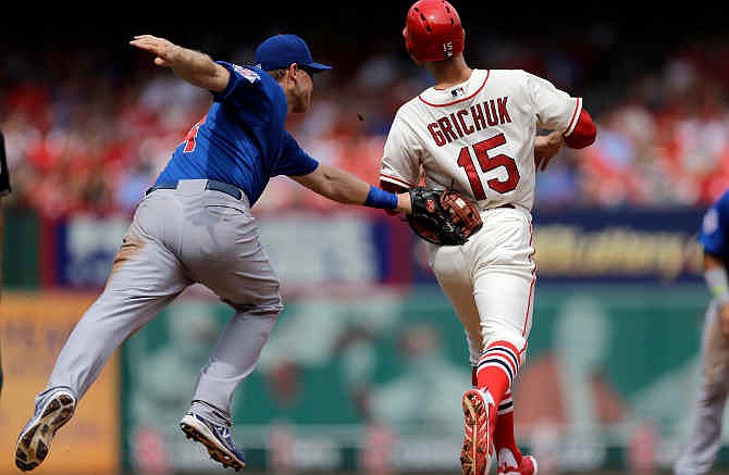 St. Louis Cardinals' Randal Grichuk, right, is tagged out by Chicago Cubs first baseman Chris Valaika after being caught in a run down between first and second during the third inning in the first baseball game of a doubleheader, Saturday, Aug. 30, 2014, in St. Louis.