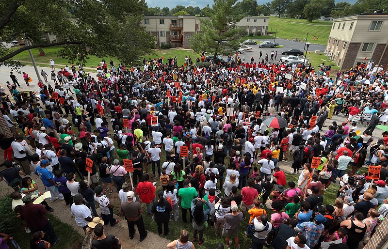 Hundreds of people gather at the Canfield Green apartments for prayer around the memorial to Michael Brown, an unarmed black 18-year-old who was fatally shot by a white police officer three weeks earlier, during a rally in Ferguson, Mo. on Saturday, Aug. 30, 2014. 