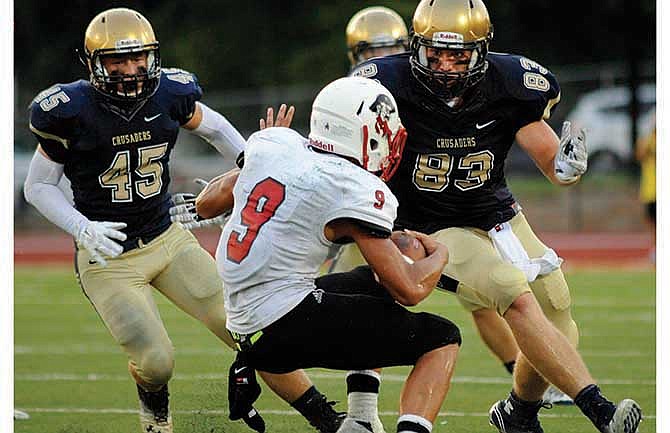Hannibal's Jerry McBride hits the brakes as Helias defensive lineman Hale Hentges (83) and linebacker Jake Burnett (45) close in for the tackle during Saturday night's game at Adkins Stadium in Jefferson City.
