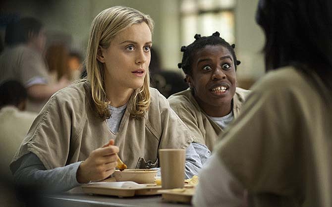 This image released by Netflix shows Taylor Schilling, left, and Uzo Aduba in a scene from "Orange Is the New Black." Americans are increasingly engaging in a practice known as television binge-watching _ going through several episodes in a single stretch, rather than one a week, as was common before the advent of digital video recorders and Internet streaming services such as Netflix and Hulu.