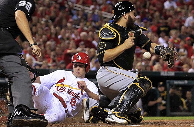St. Louis Cardinals' Peter Bourjos, left, scores on a sacrifice fly by Matt Carpenter as Pittsburgh Pirates catcher Russell Martin, right, misses the throw during the second inning of a baseball game Tuesday, Sept. 2, 2014, in St. Louis.