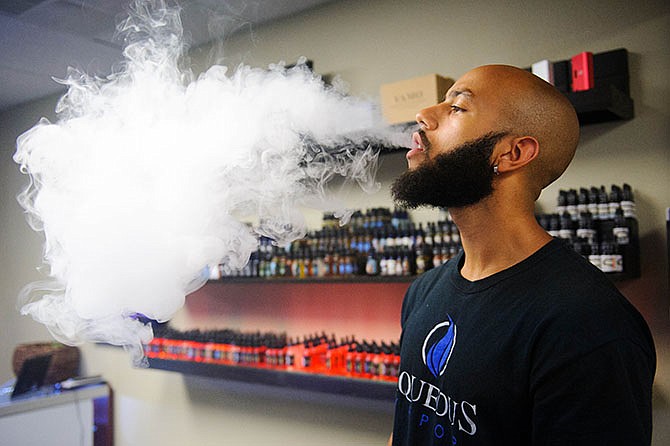 Tyler Benjamin blows smoke from his advanced personal vaporizer e-cigarette at Aqueous Vapor in Columbia. Gov. Jay Nixon is eliciting support from health professionals as he tries to persuade Missouri lawmakers to sustain his veto of legislation dealing with electronic cigarettes. 