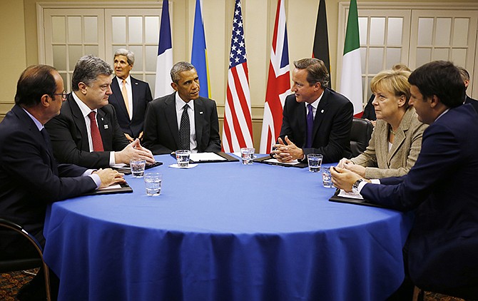 U.S. President Barack Obama, fourth from left, is seated at a table with, from left: France's President Francois Hollande; Ukraine President Petro Poroshenko; British Prime Minister David Cameron; German Chancellor Angela Merkel; and Italian Prime Minister Matteo Renzi as they meet about Ukraine at the NATO summit at Celtic Manor in Newport, Wales, Thursday. U.S. Secretary of State John Kerry is seated at rear left.