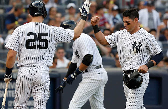 New York Yankees' Jacoby Ellsbury, right, is greeted by Mark Teixeira after scoring on a sacrifice fly during the third inning of the baseball game against the Kansas City Royals at Yankee Stadium, Saturday, Sept. 6, 2014 in New York. 