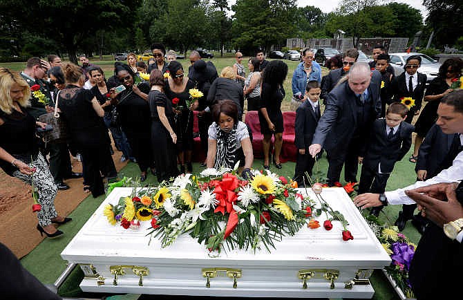 Friends and family leave flowers on the casket during a funeral service for Maria Fernandes, 32, Friday, Sept. 5, 2014, in Linden, N.J. Fernandes died while napping in her car between jobs. Elizabeth police believe Fernandes pulled over for a nap after a shift at a Dunkin Donuts in Linden. She also worked at Dunkin Donuts in Harrison and Newark. Police say it appears Fernandes was overcome by a deadly mixture of carbon monoxide and fumes from an overturned gasoline container.