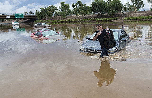 Jim Sampson retrieves items from his 2002 Toyota Corolla stuck in flood waters on I-10 after monsoon rains flooded the freeway in Phoenix on Monday. Heavy storms pounded the Phoenix area early Monday, flooding major freeways, prompting several water rescues and setting an all time single-day record for rainfall in the desert city.