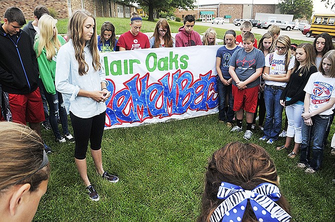 Blair Oaks High School student council president Jolie Duffner, inside circle, asks fellow students to bow their heads in a reflective moment Thursday at the Cole County high school. Students put out nearly 3,000 pocket flags, one for each person killed in the 9/11 attacks.