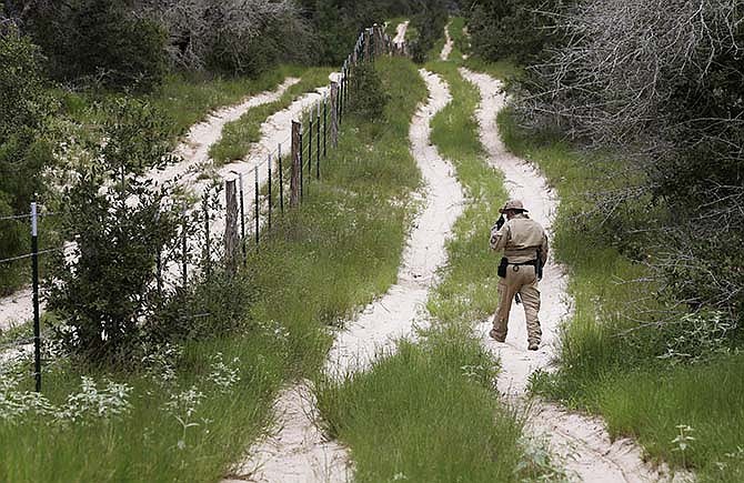 In this Sept. 5, 2014 file photo, a U.S. Customs and Border Protection Air and Marine agent looks for signs along trail while on patrol near the Texas-Mexico border near McAllen, Texas.