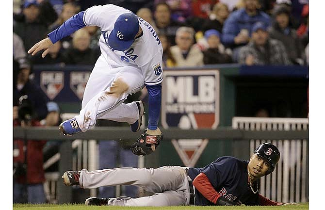 Kansas City Royals third baseman Mike Moustakas leaps over Boston Red Sox's Mookie Betts after tagging Betts out when he was caught between third and home during the fifth inning of a baseball game Friday, Sept. 12, 2014, in Kansas City, Mo. 