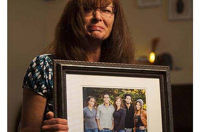 In this photo, taken, Friday, Sept. 12, 2014, shows Susan Hunt holding a photo of her family, including her son, Darrien Hunt, at her home in Saratoga Springs, Utah. Darrien Hunt was killed by police Wednesday. Susan Hunt has criticized police in the Utah County city of Saratoga Springs over the fatal shooting of her 22-year-old son, saying she believes the outcome would have been different had he not been black.