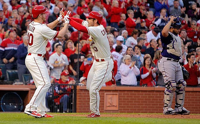 Colorado Rockies catcher Wilin Rosario, right, stands nearby as St. Louis Cardinals' Shelby Miller, left, high-fives Matt Carpenter after Carpenter hit a two-run home run during the second inning of a baseball game Saturday, Sept. 13, 2014, in St. Louis.
