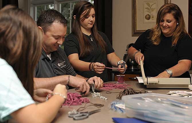 Maci, Mike, McKenzi and Suzi Marsch work together to craft bracelets as a way to both spread awareness of Agape International Missions' work and help raise funds to support Pete and Debbie Livingston as they prepare for their move to Cambodia to work with Agape.