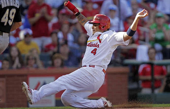 St. Louis Cardinals' Yadier Molina (4) scores from third on a wild pitch from Colorado Rockies relief pitcher Rex Brothers in the eighth inning of a baseball game, Sunday, Sept. 14, 2014, in St. Louis. The Cardinals won 4-1. 