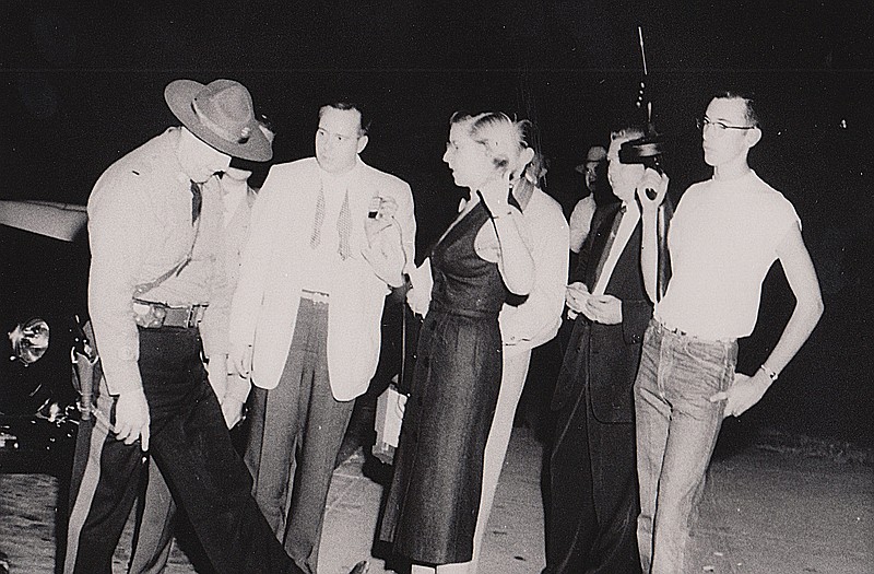 Jerena East Griffen, the first female reporter in Missouri for UPI, interviews a Highway Patrol officer with other media during the night of the Sept. 22, 1954, riot at the Missouri State Penitentiary. Far right, 17-year-old John Eidson, son of Warden Ralph Eidson, holds a Thompson machine gun for the trooper.